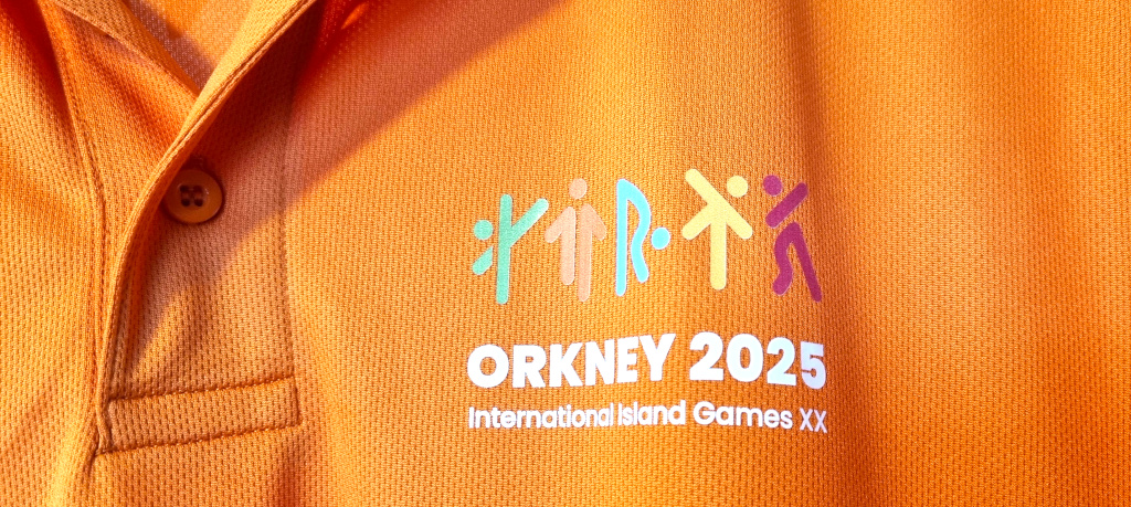 A picture of an Orkney 2025 volunteer's orange T-shirt featuring the runic sports logo.