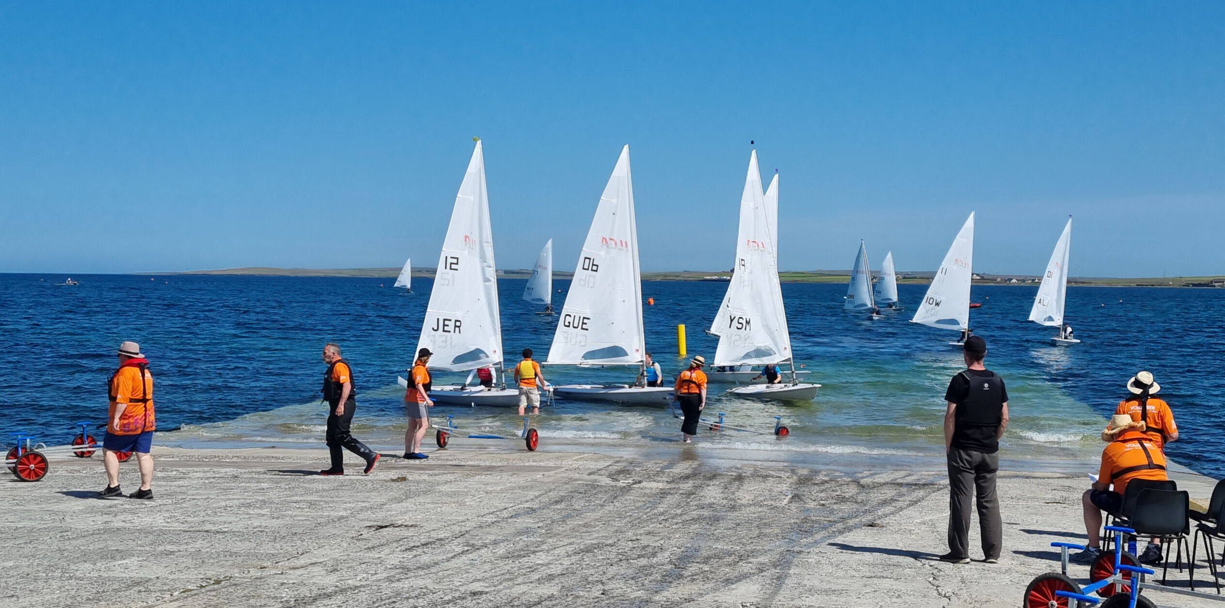 Recovering ILCAs at Hatston Orkney 2025 Island Games volunteers help haul ILCA racing dinghies out of the water at Hatston slipway in Orkney.