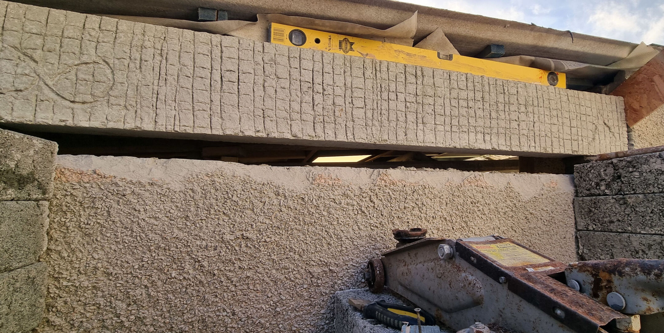 The concrete lintel has been raised up and placed level on its end bearers.