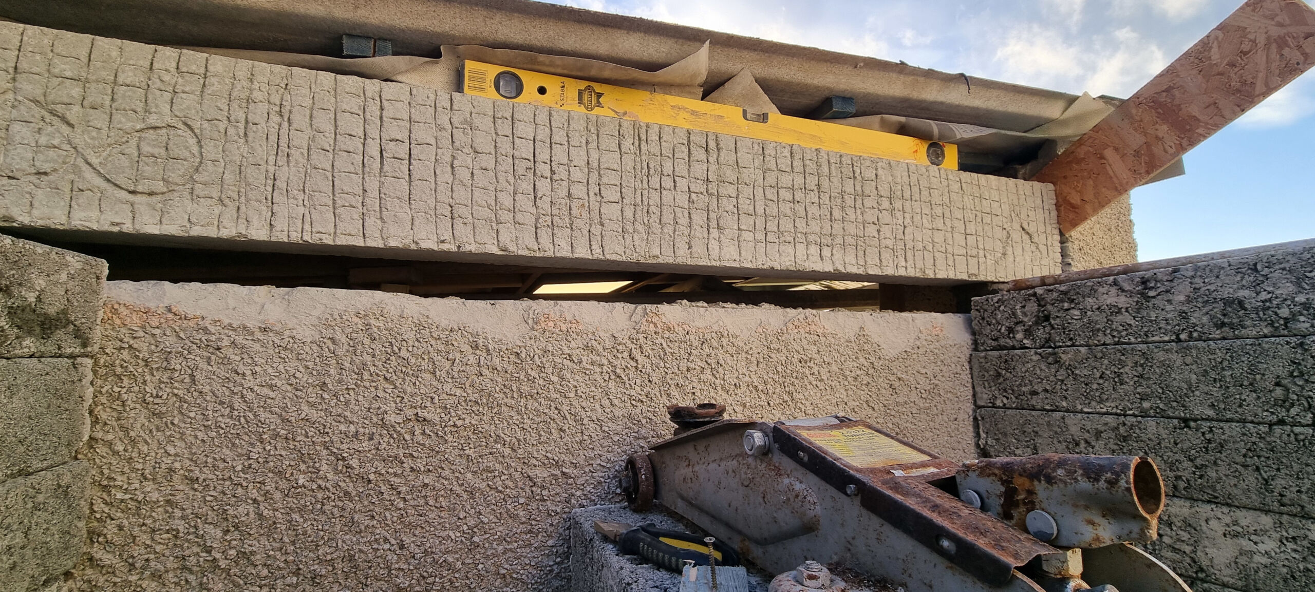 The concrete lintel has been raised up and placed level on its end bearers.
